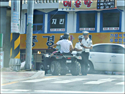 헬멧 미착용으로 단속 받은 후 착용하고 주의사항을 듣고 있는 운전자 